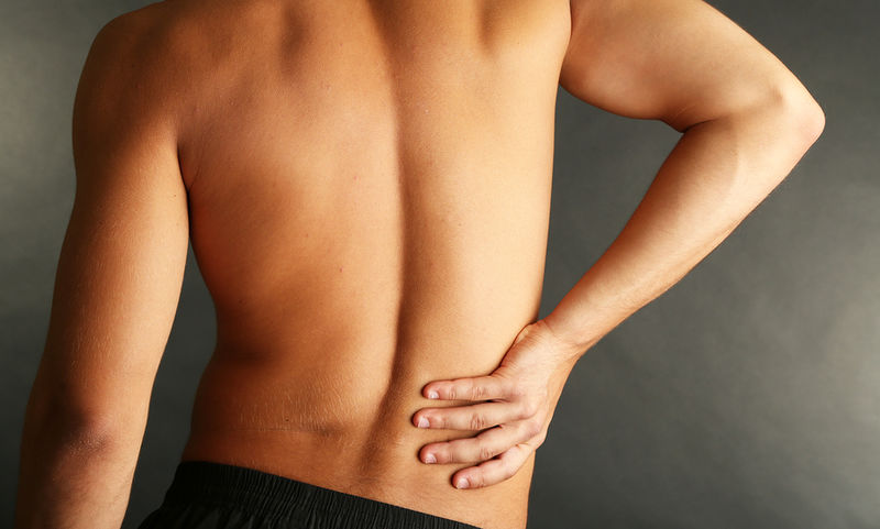 bigstock-young-man-with-back-pain-on-gr-52560715